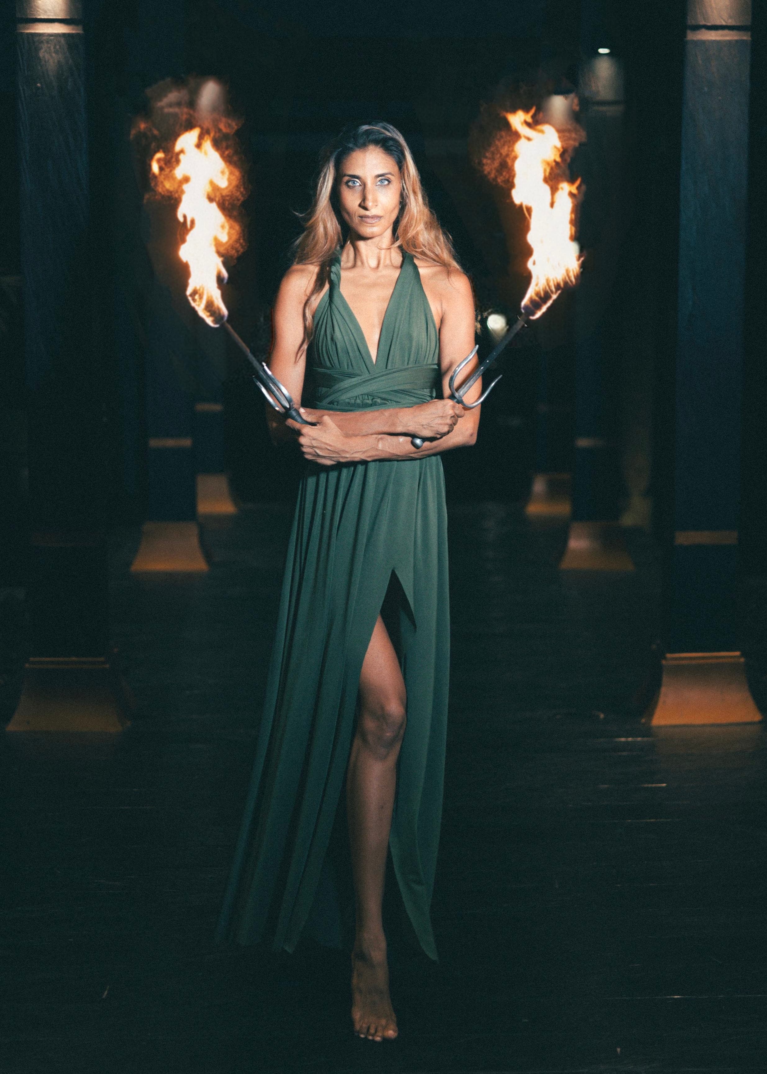 Mistress Ruby Noir in a green gown holding two flaming torches