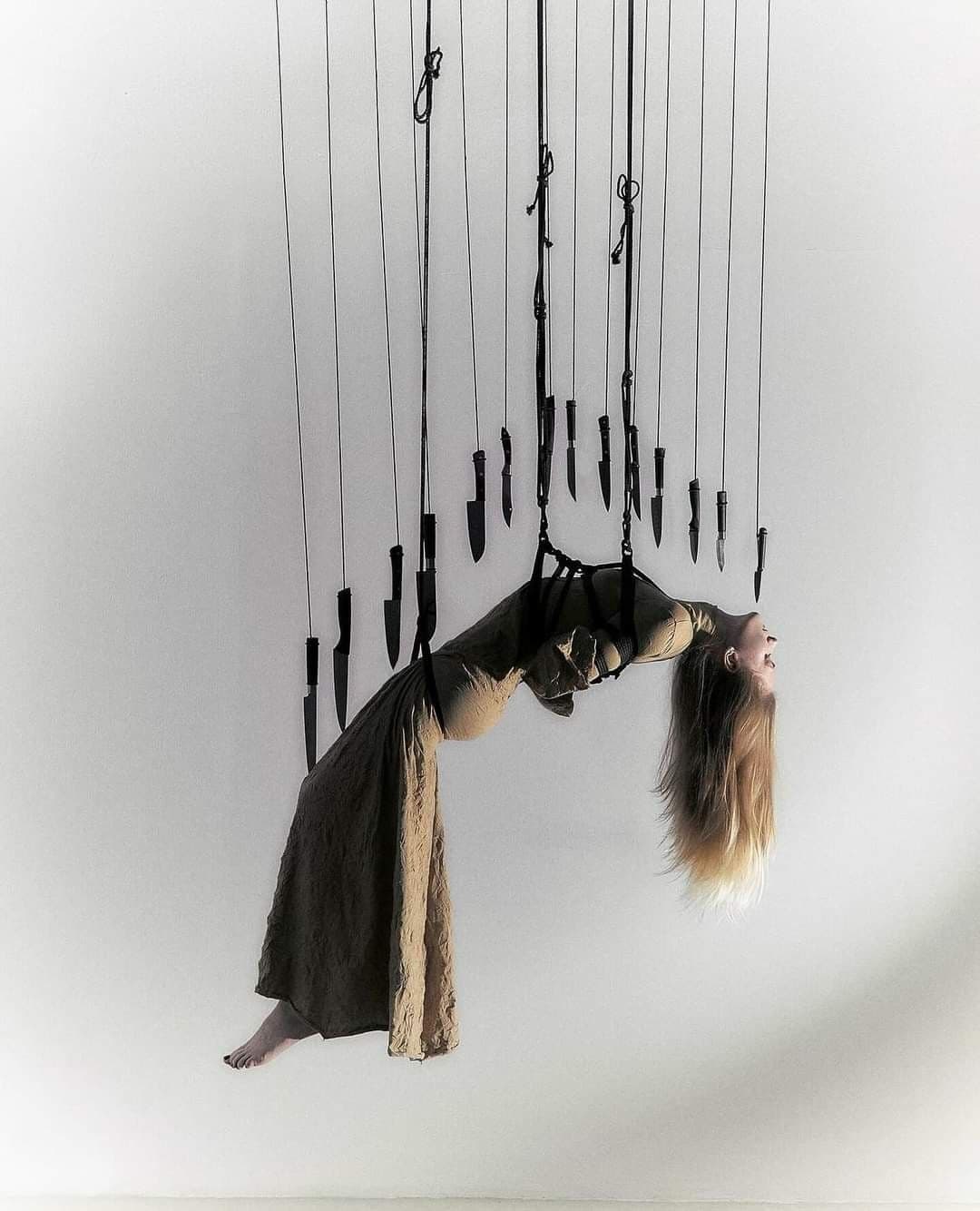 A suspended woman beneath hanging blades
